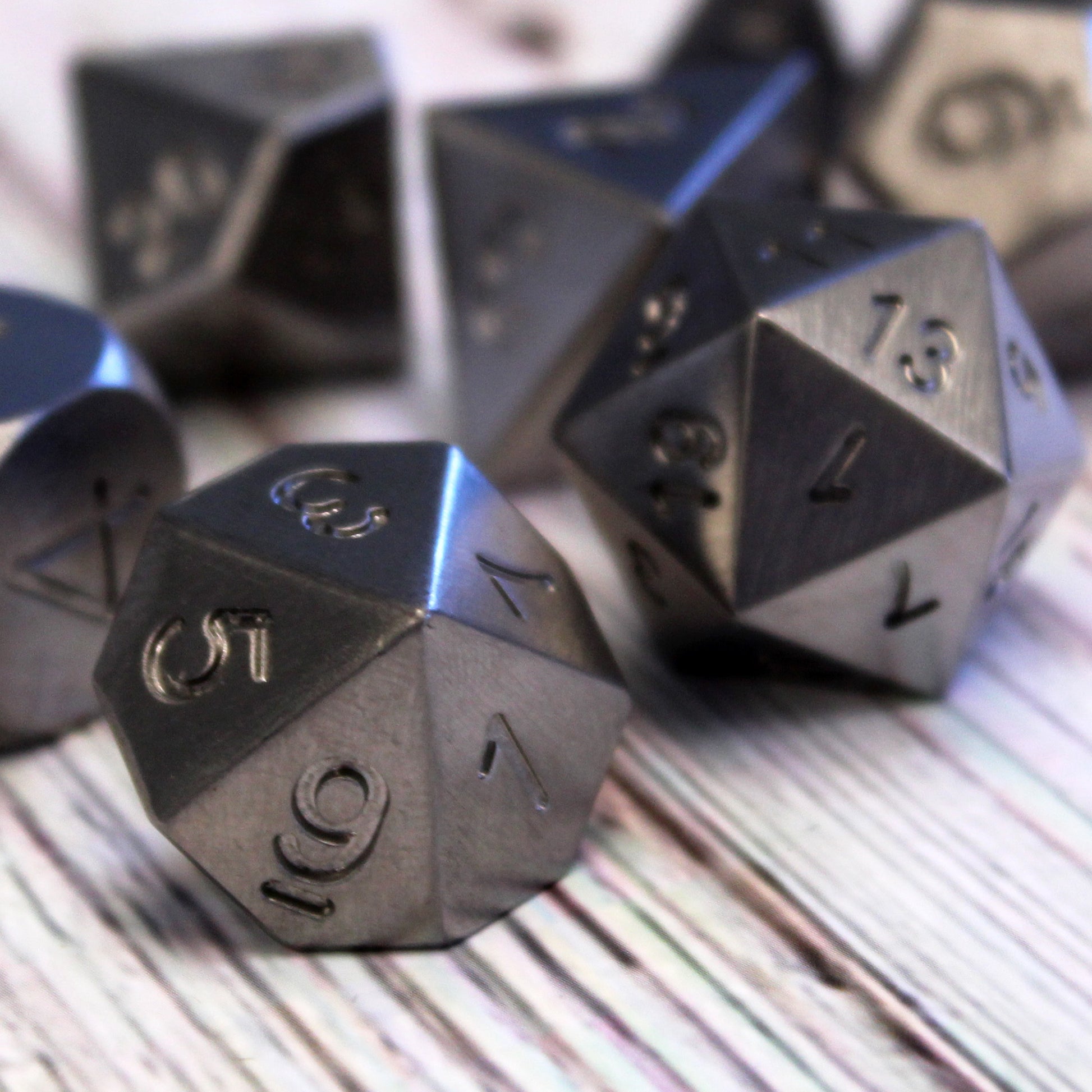 Close up shot of Tungsten RPG dice set resting on a wooden surface with the d10 in front viewed at the apex of the odd faces of the die.