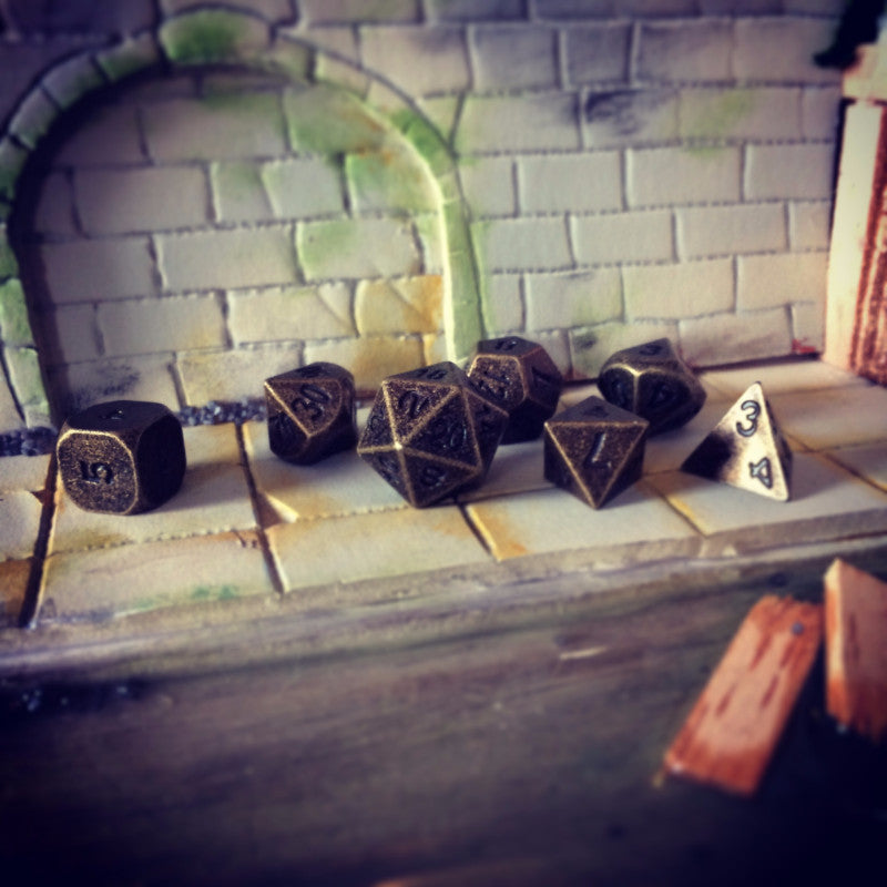 Primordial gold dice set arranged on a mini sewer dungeon set piece