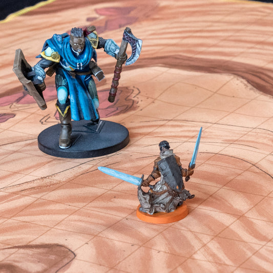 Closeup photo of a desert battle map with two miniature figures on it