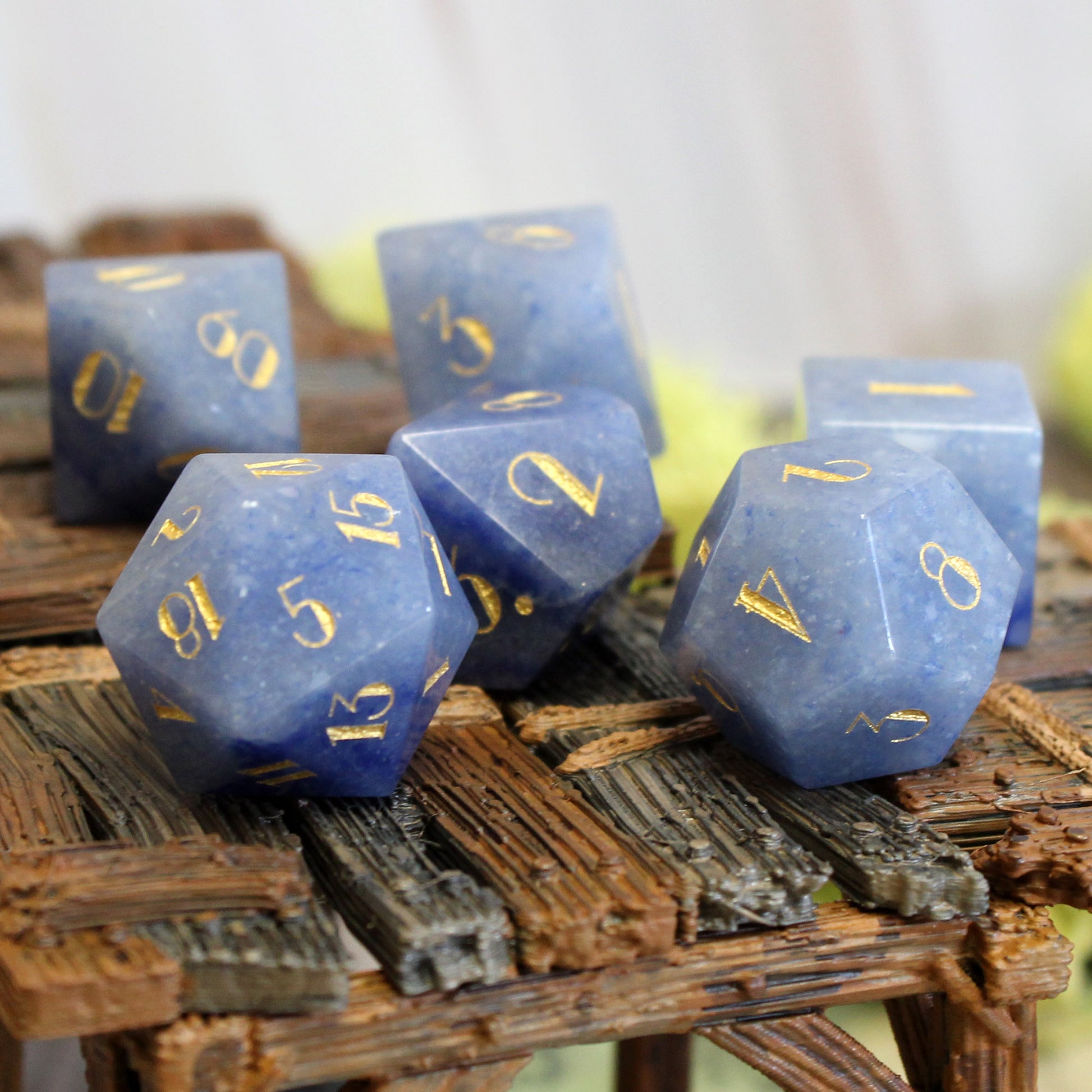 Deep blue gemstone dice set with gold foil lettering on a dungeons and dragons game table.