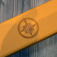Close-up of a yellow leatherette dice case with a engraved logo on a wood background