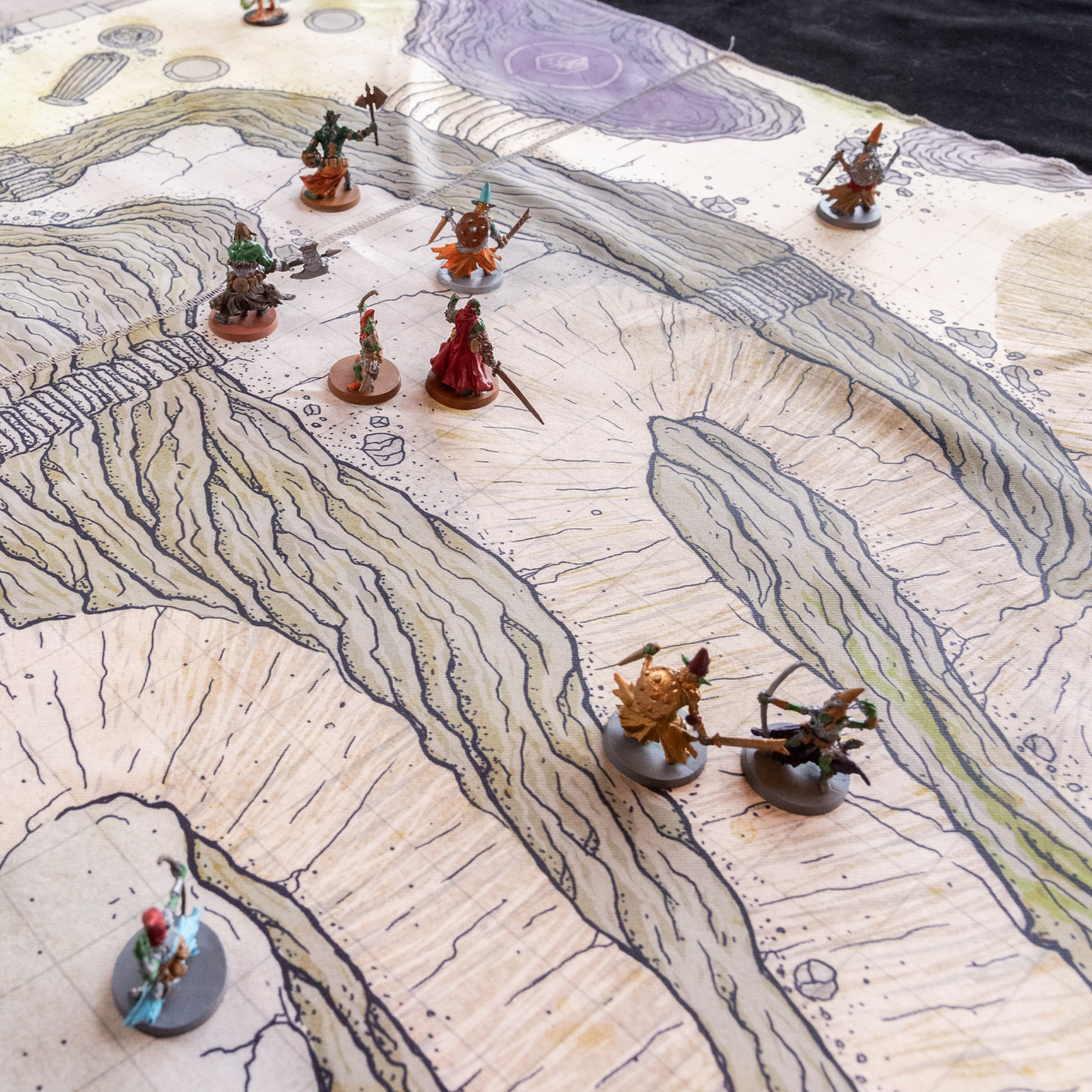 Isometric photo of a cliffside battle map with multiple miniature figures on it 