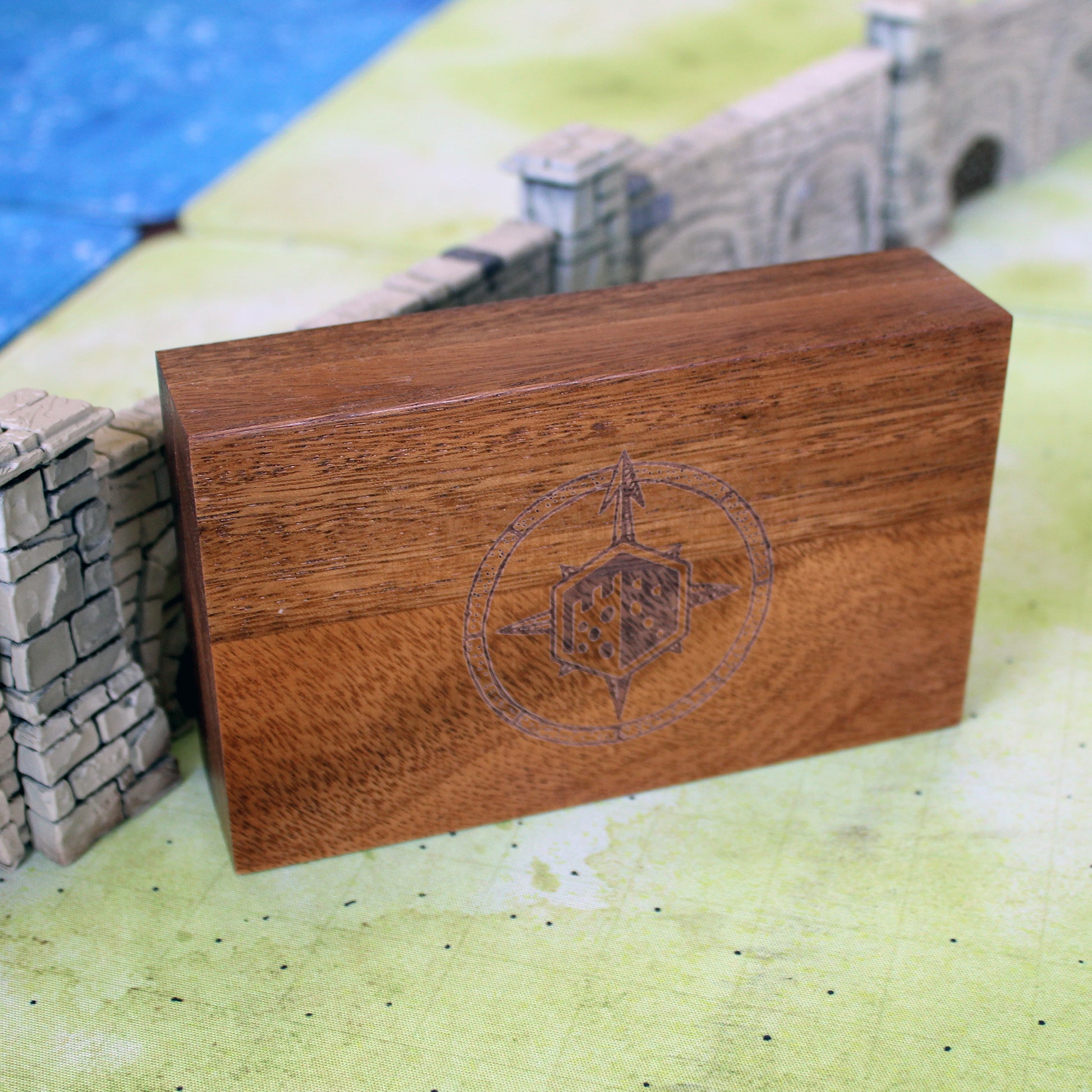 Wooden box with a compass rose logo on a miniature landscape background