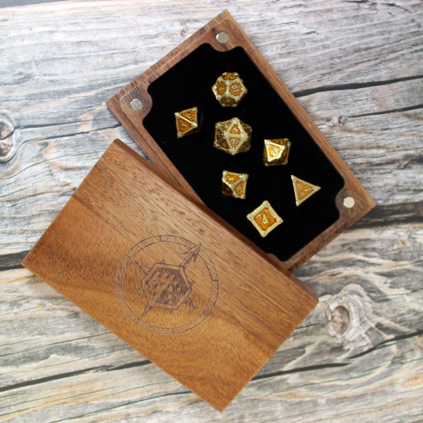 Set of gold dice with a wooden dice box on a wooden surface.