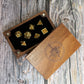 Wooden dice box with engraved design containing gold and silver dice on a wooden surface