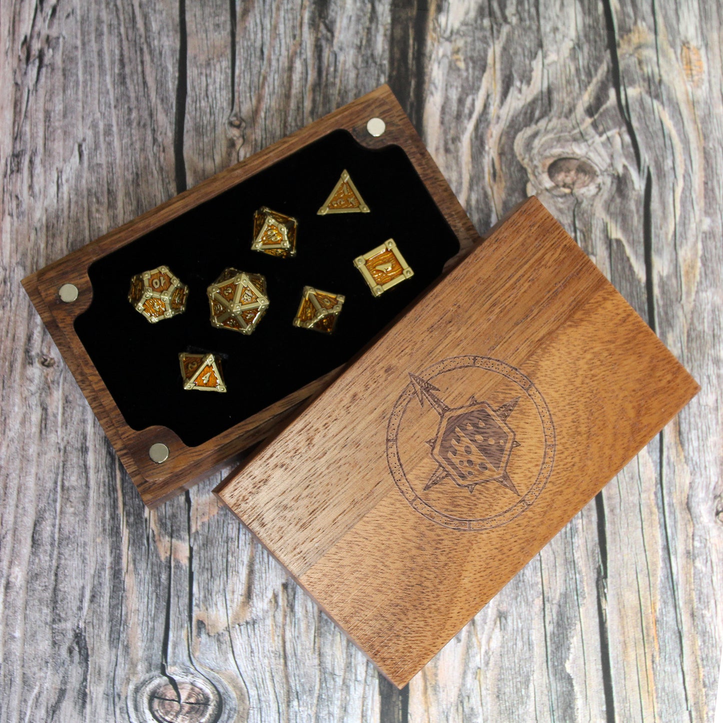 Wooden dice box with engraved design containing gold and silver dice on a wooden surface