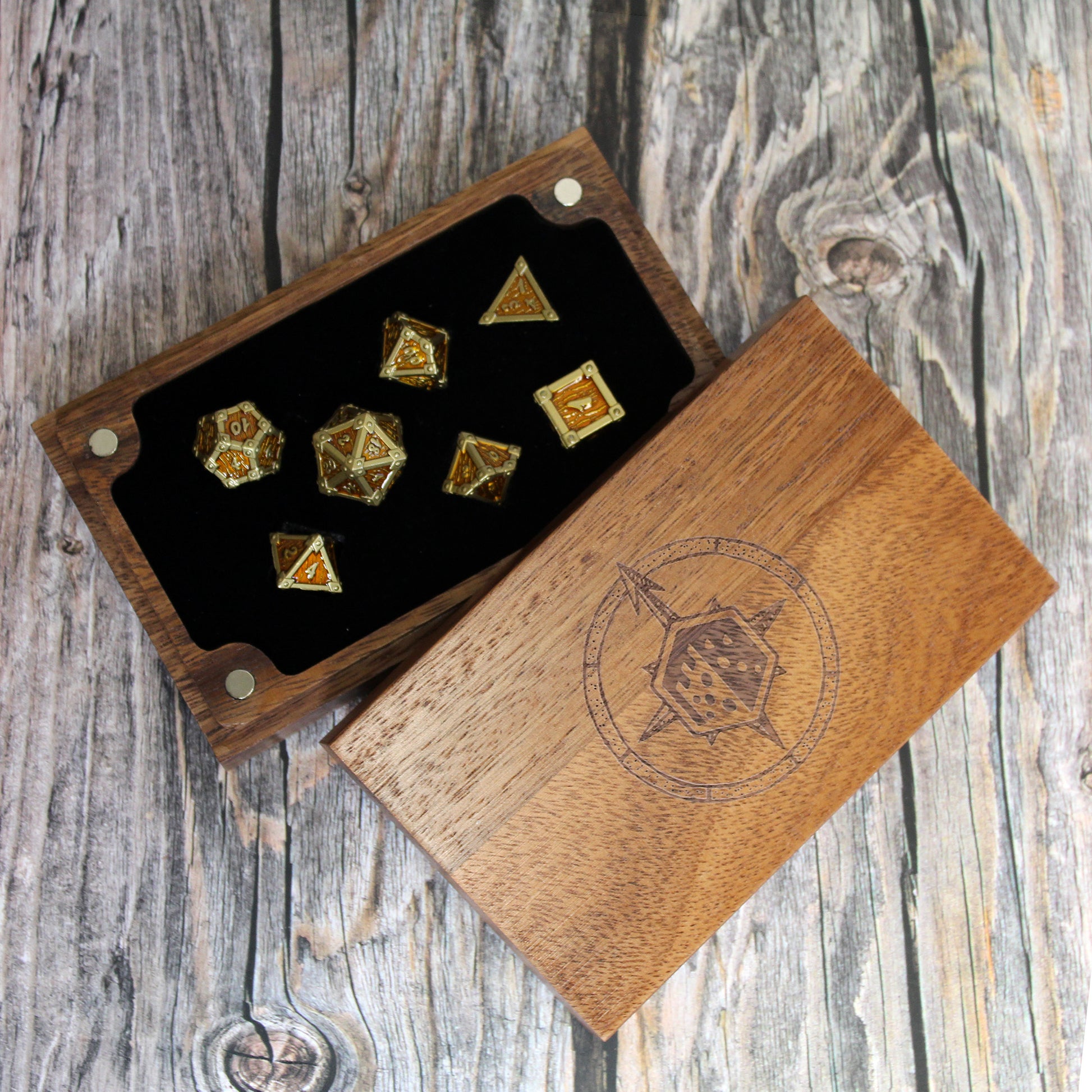Wooden dice box with engraved design containing gold and silver dice on a wooden surface