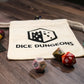 An empty cotton dice bag laying flat on a table with "Dice Dungeons" visible on its front and a few polyhedral dice scattered around it.