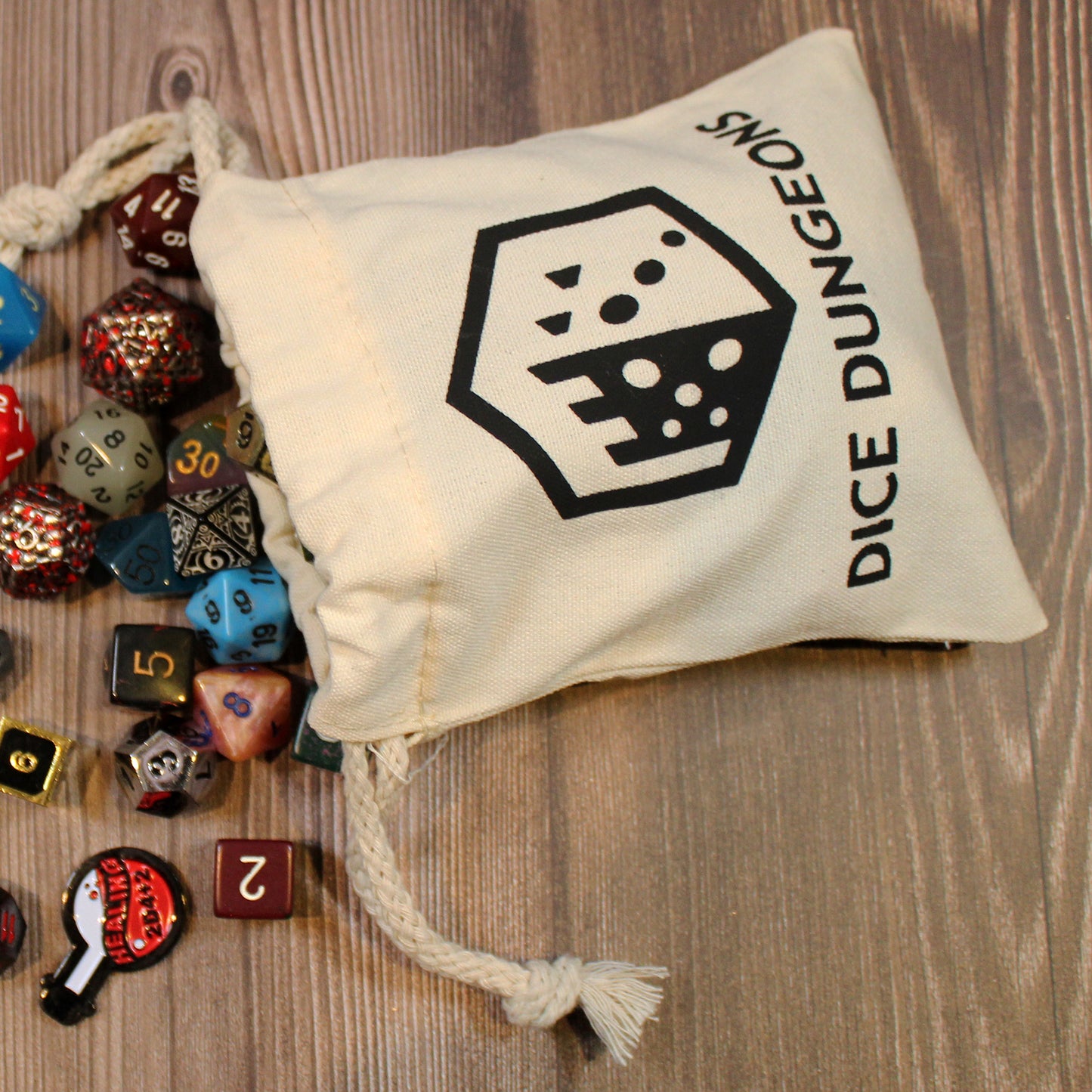 A full cotton dice bag viewed from above with a variety of polyhedral dice spilling from its opening.