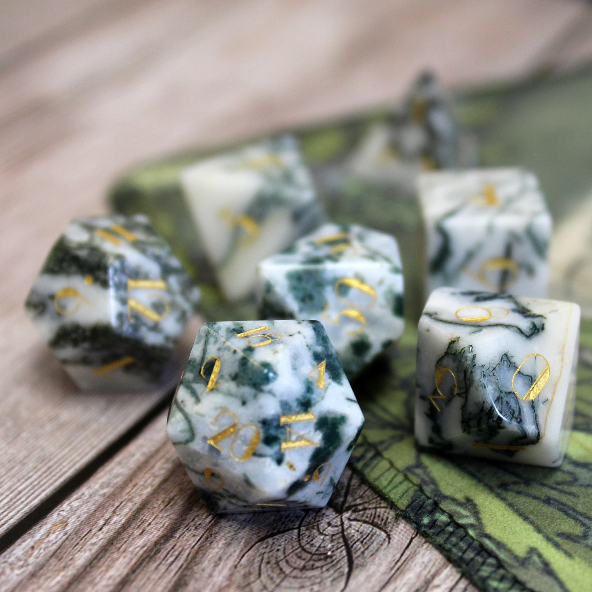 Dentrite Agate Gemstone Dice Set displayed on a table and Dungeons & Dragons battlemap, combining natural stone beauty with opulent gold fonts