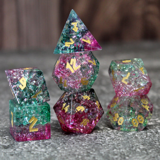 Stacked Frost Bound Fae Friend Shattered Glass dice set, featuring flamingo pink and emerald green hues with intricate fissures that sparkle like Faerie Fire in the light.