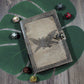 Decorative notebook with a moth-man design on a wooden surface with dice around it. Used for dungeons and dragons and tabletop game notes.