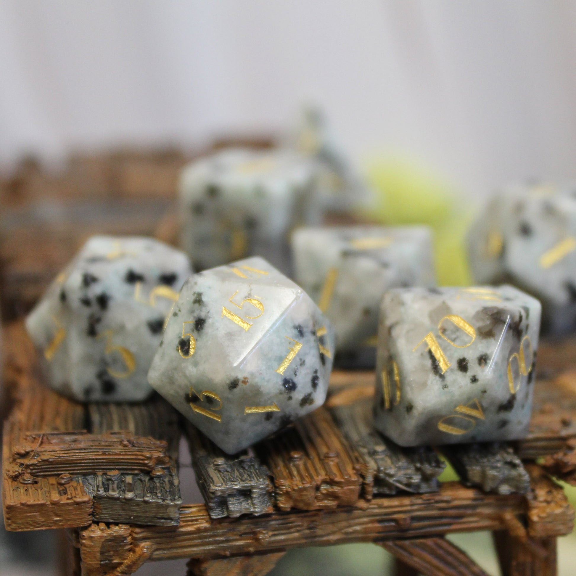 Milky Jasper Gemstone Dice Set displayed on a game table, featuring elegant gold numbering and intricate stone patterns for your next DnD session.