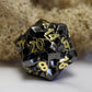 Close-up of NightBane d20 black metal die with intricate detailing, featuring golden electroplated numbers against a sleek black metal base.