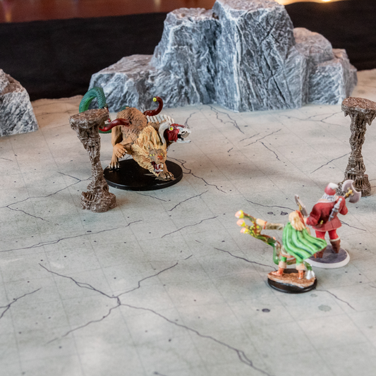 Photo of a cave floor battle map with model boulders and various miniature figures on it