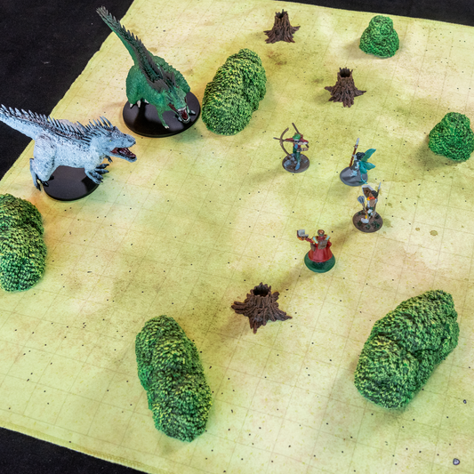 Photo of a field battle map with multiple model trees and various miniature figures in a fight scene
