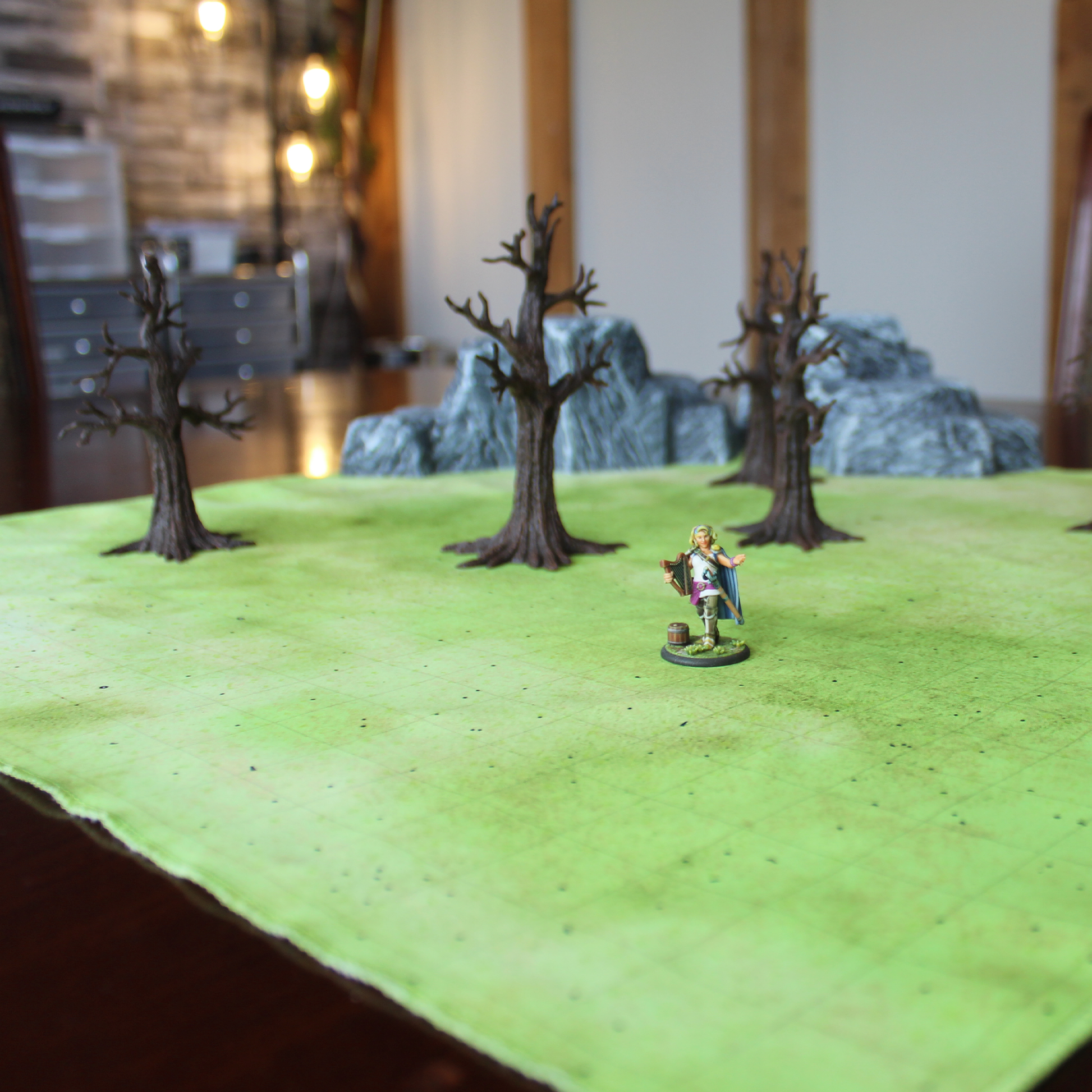 Photo of a field battle map with a lone miniature figure and three barren trees