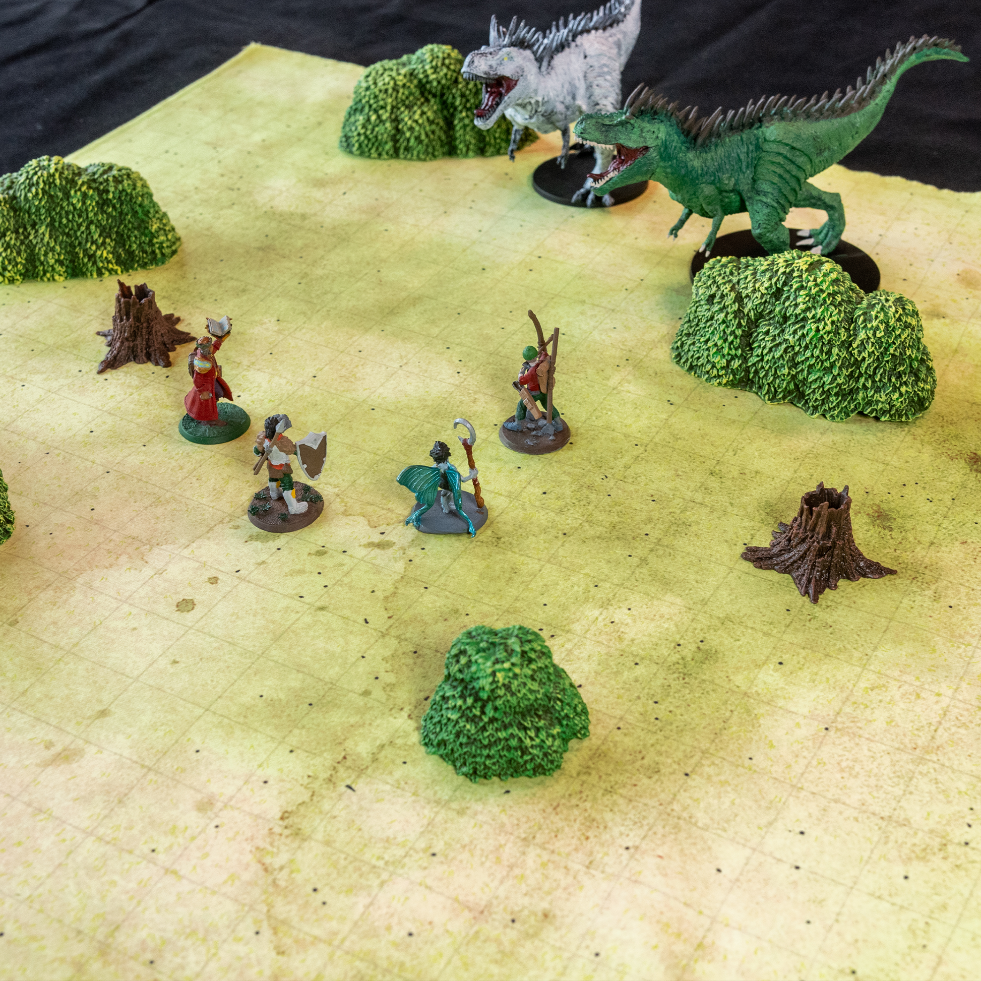 Isometric photo of a field battle map with four miniature figures combatting two t-rex figures
