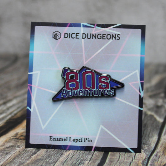 An enamel pin of an "'80s Adventures" logo on a cardboard backing with a geometric neon design