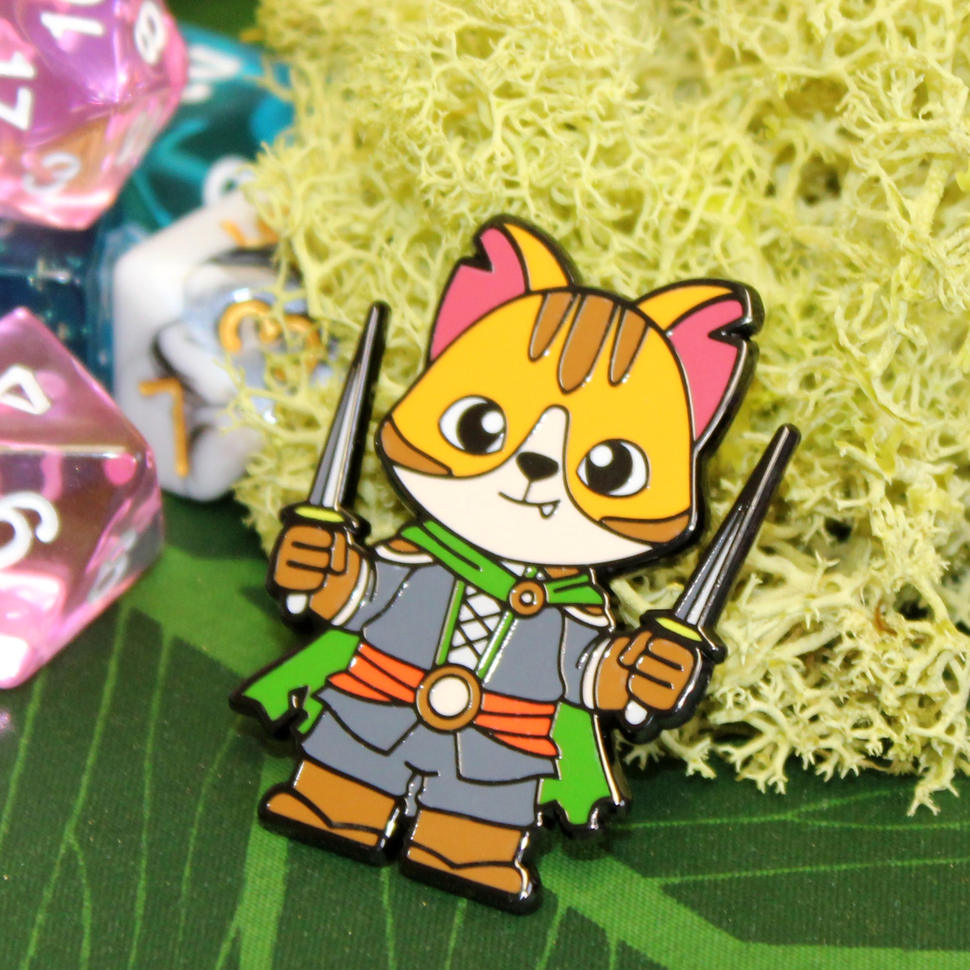 Adventure Cats rogue pin displayed on a moss-covered game table, with RPG dice in the background for a fantasy-themed setting.