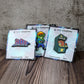 Three enamel pins propped p against a wall