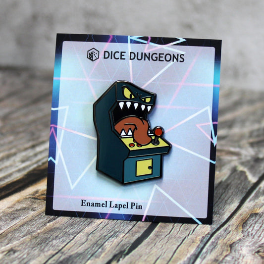 An enamel pin of a standup arcade machine mimic on a cardboard backing with a neon-colored geometric design. 
