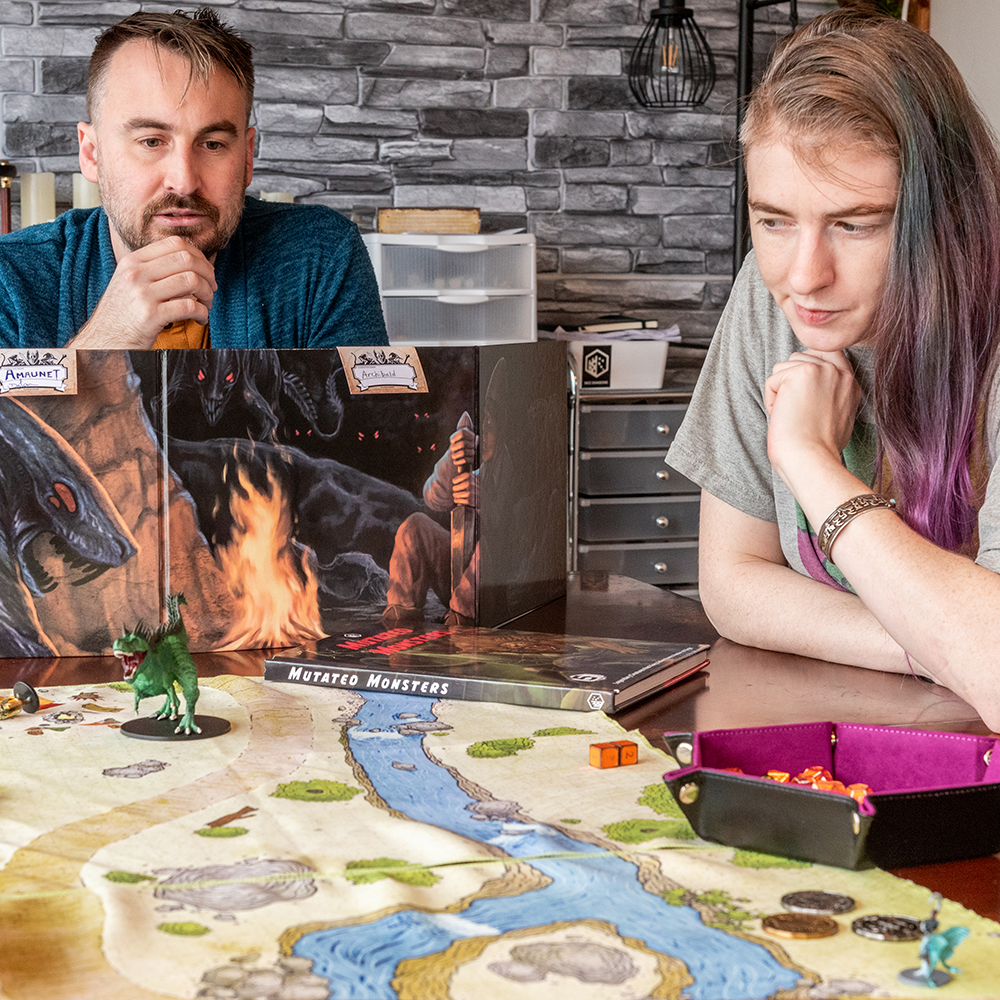 Photo of two people playing a tabletop RPG using a campsite battle map