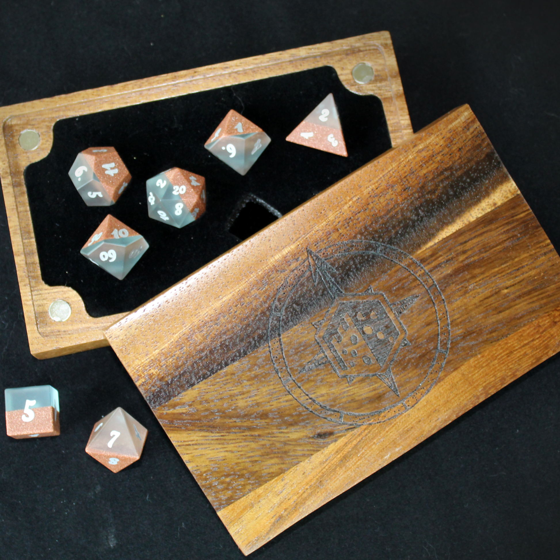 Set of polyhedral dice with a wooden box on a black background