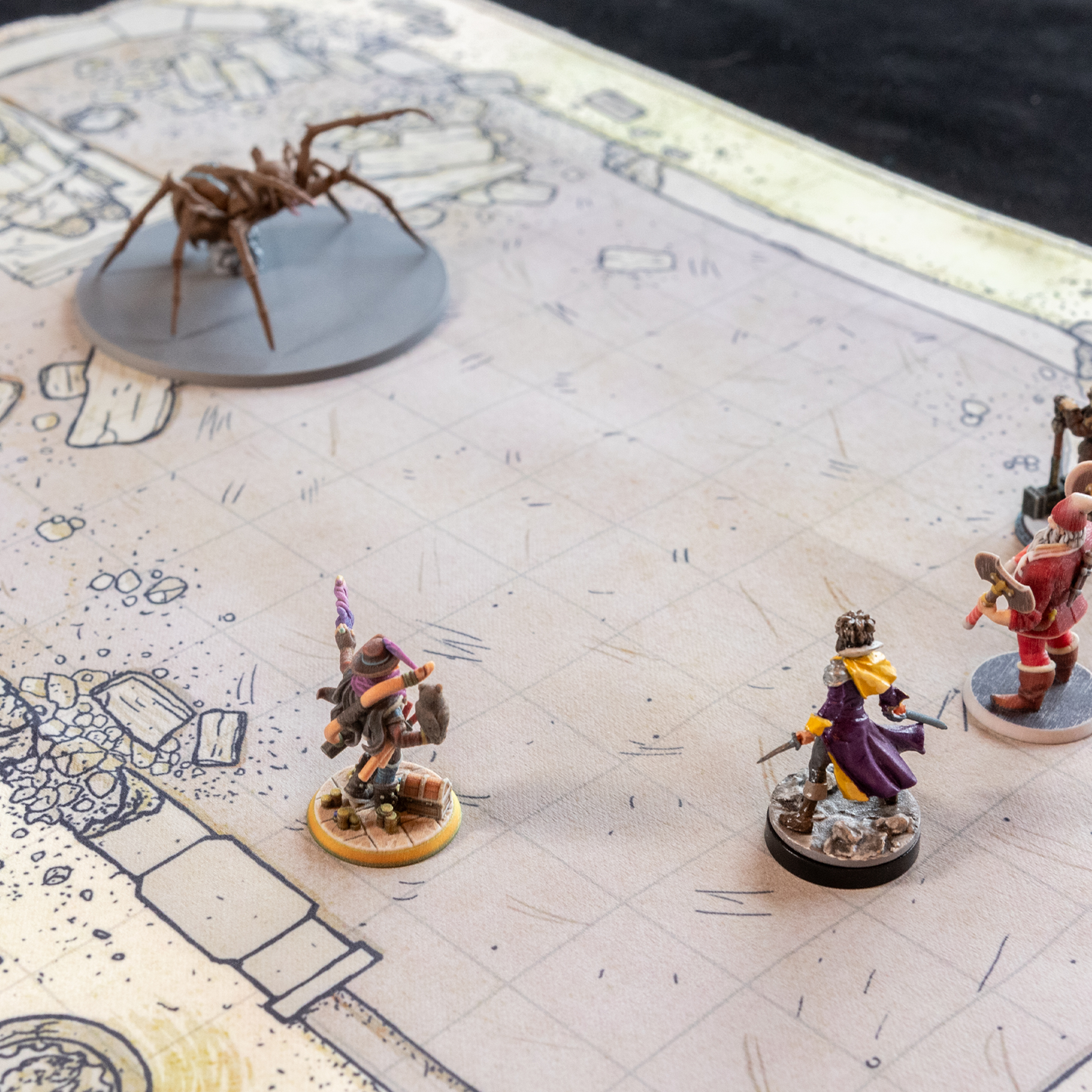 Closeup photo of a spider miniature and four adventurers on a ruined temple battle map