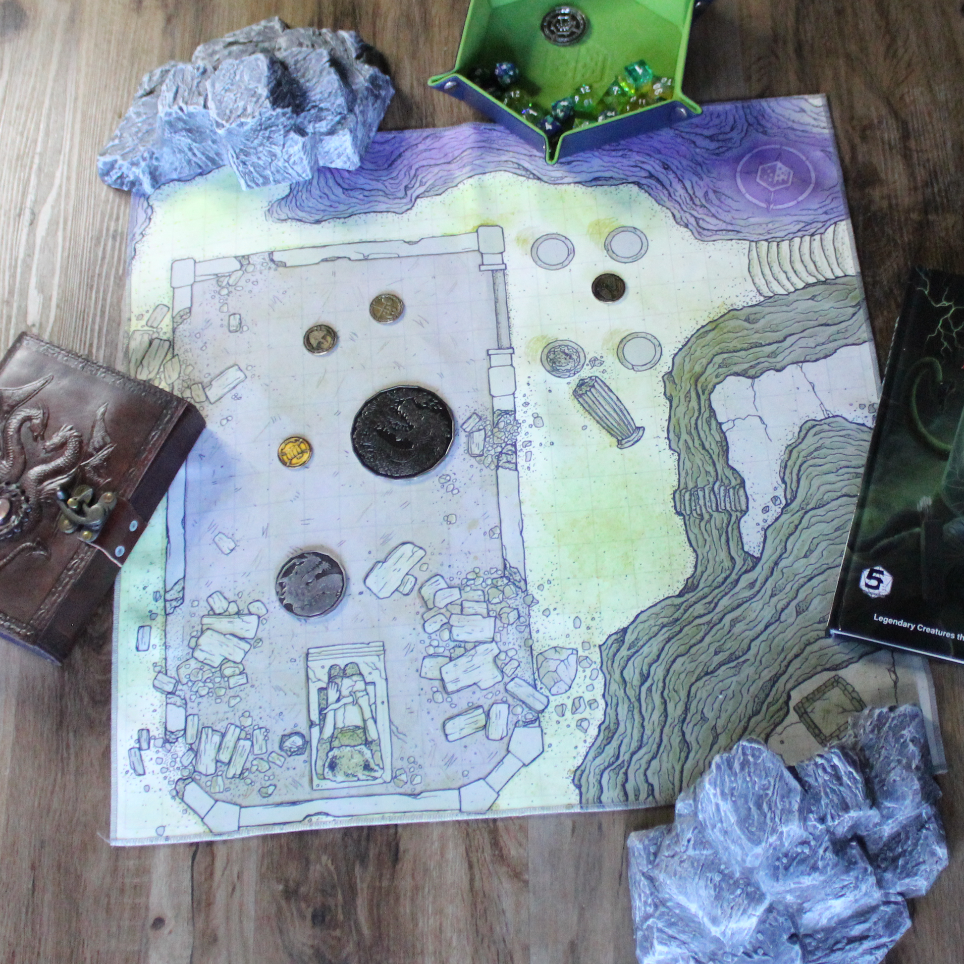 Overhead photo of a ruined temple battle map with tabletop RPG gear scattered around it