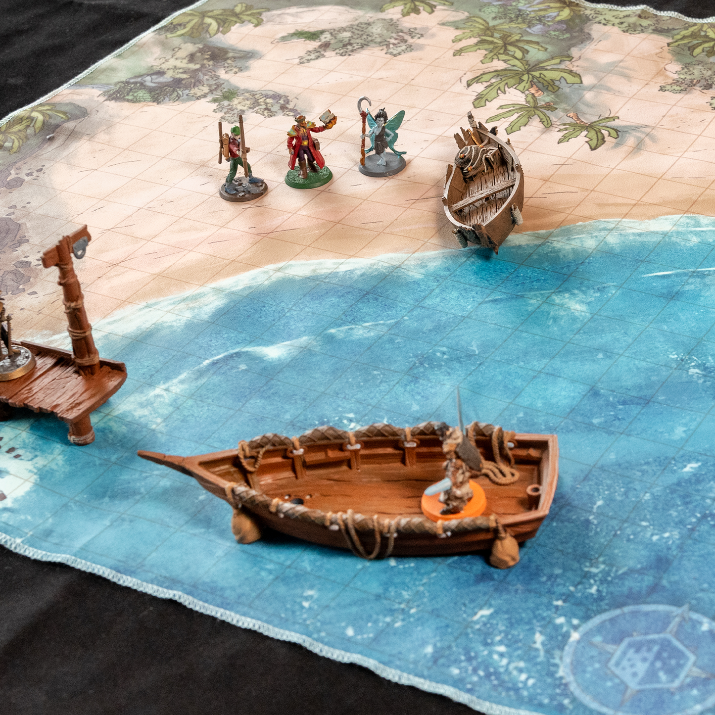Image of a beach battle map with several miniature figures on it as well as two model boats