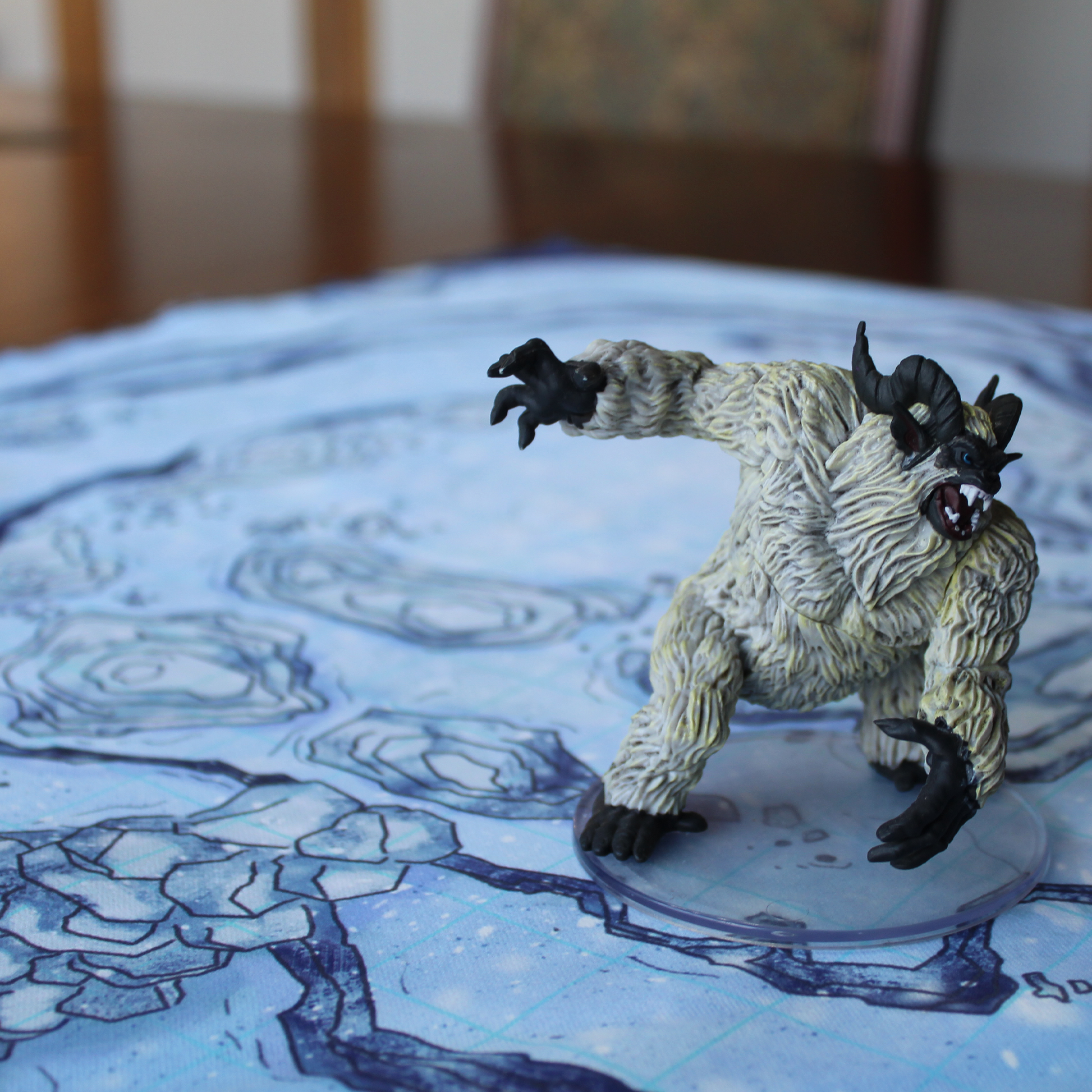 Closeup photo of a snowy battle map with a miniature yeti figure on it