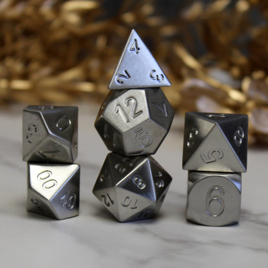 stainless steel dice with uninked numbers for dnd games, stacked on game table.