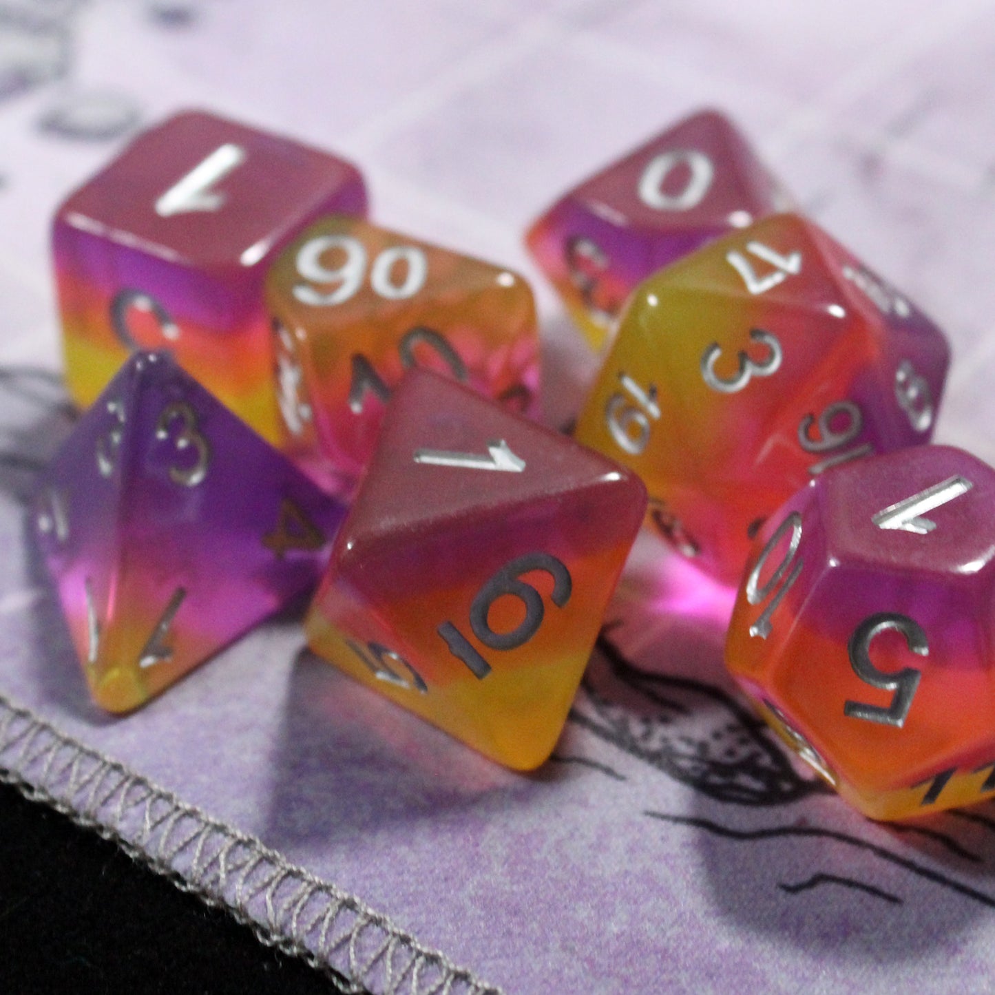 Set of pink and orange polyhedral dice on a play mat