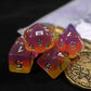 Set of pink and orange polyhedral dice with some golden tokens on a play mat