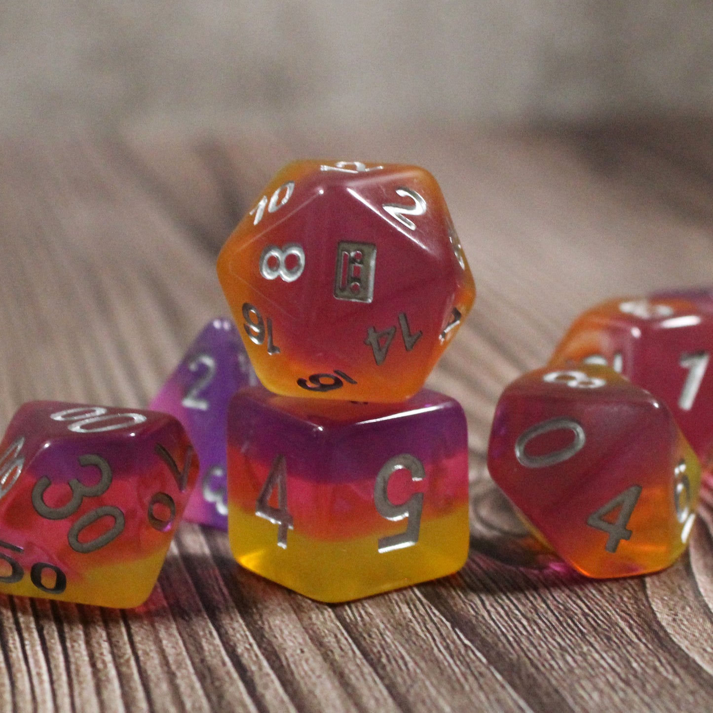 Set of pink and orange polyhedral dice on a wooden surface