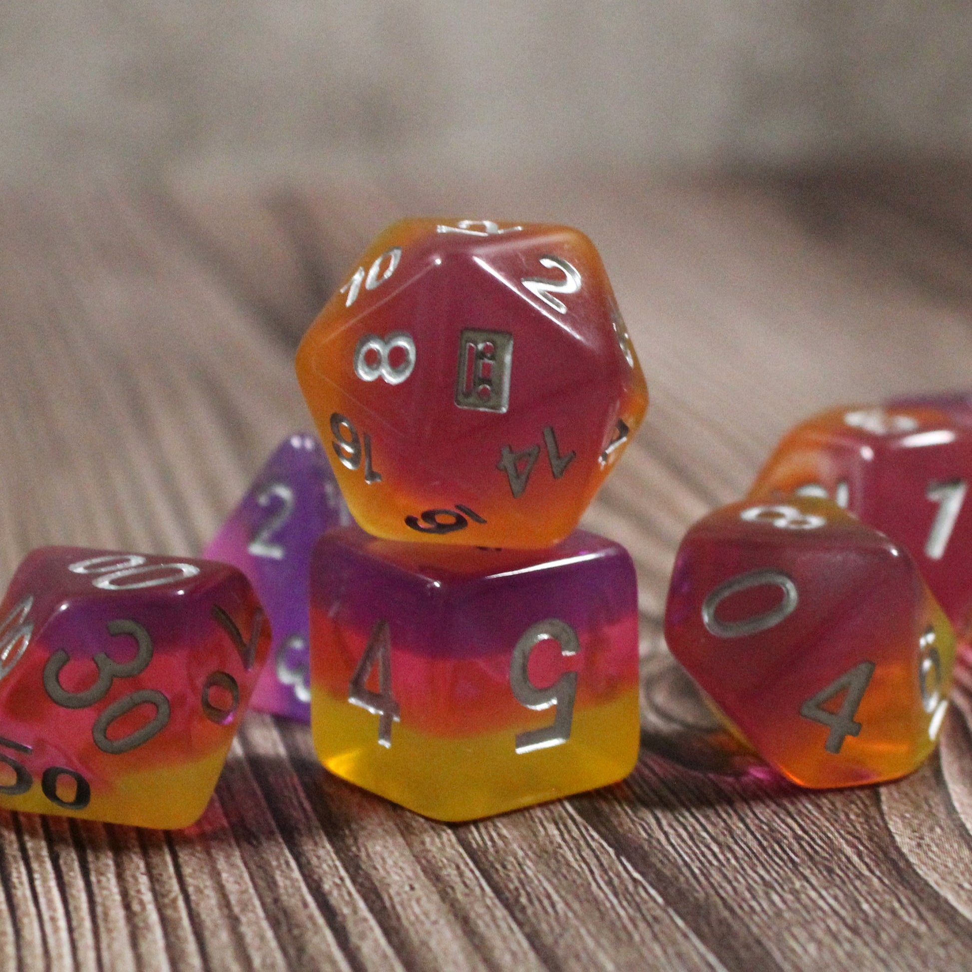 Set of pink and orange polyhedral dice on a wooden surface