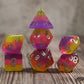 Set of pink and orange polyhedral dice neatly stacked on a wooden surface