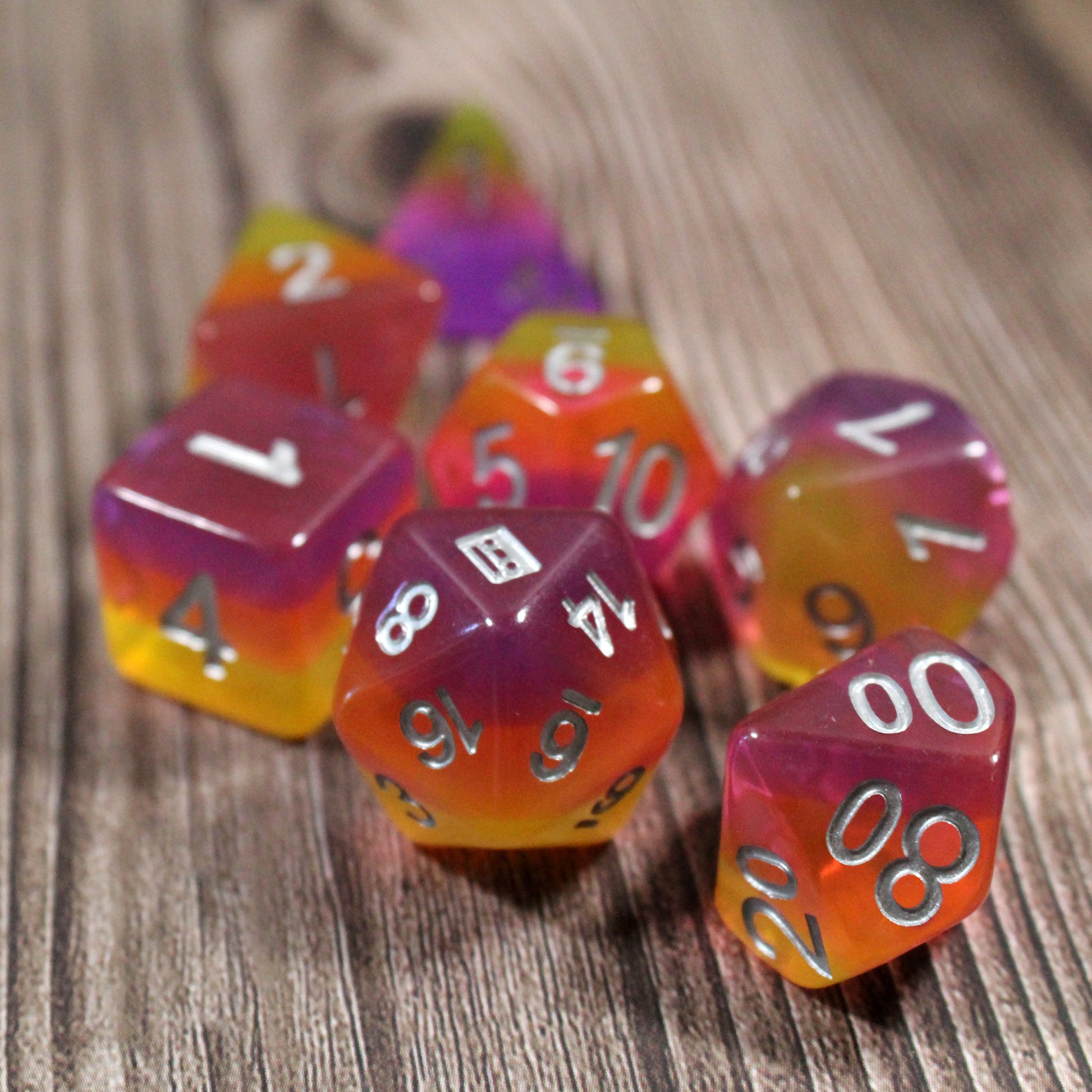 Set of pink and orange polyhedral dice on a wood-textured surface