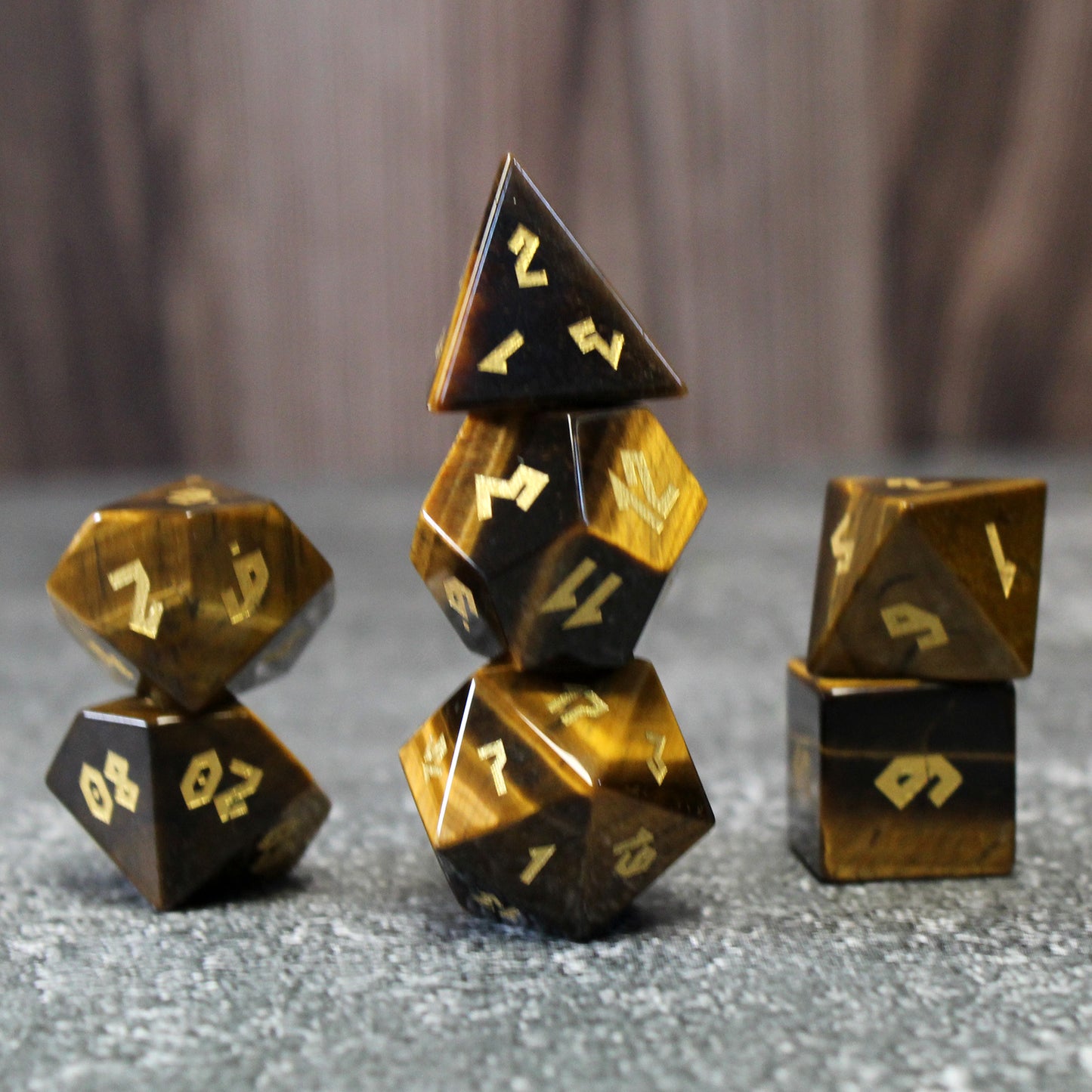 Stacked Tiger Eye dice set on a table, perfect for Dungeons & Dragons, with gold-inked numbers highlighting the stone’s elegant stripes.