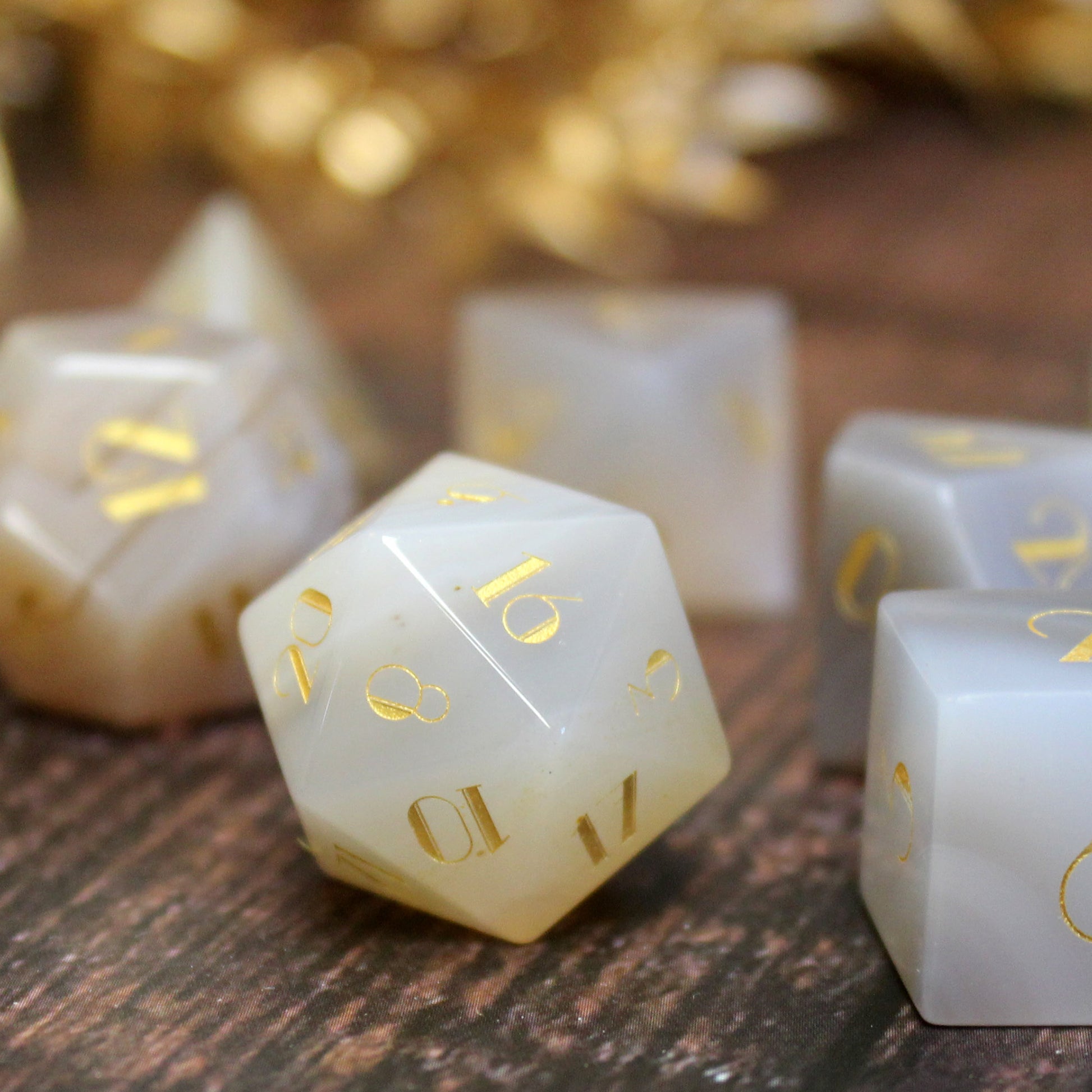 Close-up of White Stripe Agate d20 on a game table, highlighting the intricate stone patterns and vintage gold numbering, designed for tabletop RPGs.