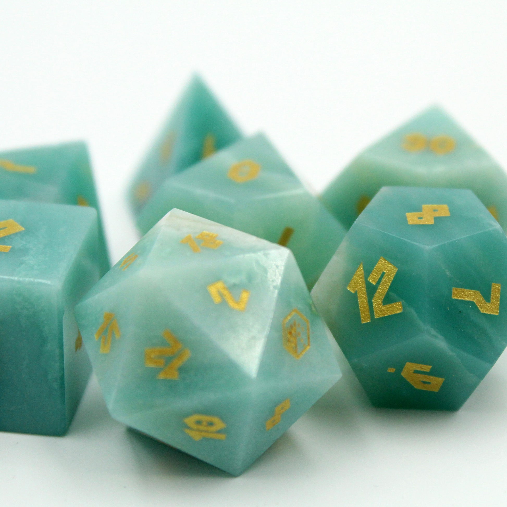 Close-up of Amazonite gemstone dice from the set, featuring Grecian-style font inked in gold on a white background.