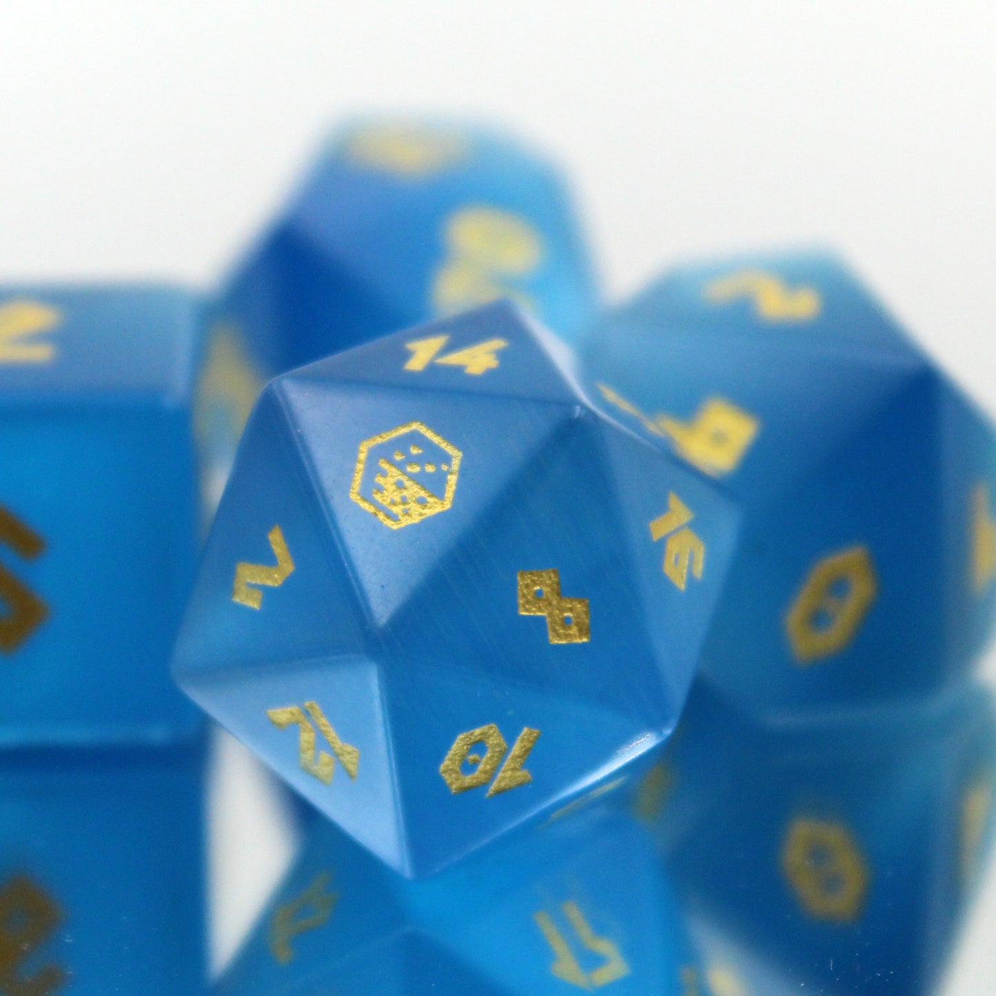 Close-up of the Cat's Eye Blue dice set with the D20 highlighted, featuring a subtle ombre from sea blue to sky blue with gold numbering.