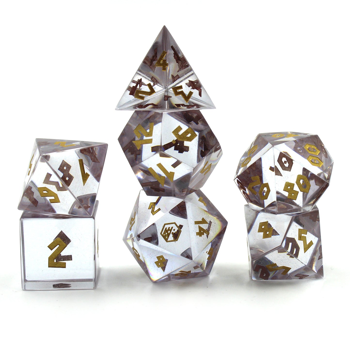 Picture of the Cubic Zirconia dice set on a white surface and background.  The dice are fully transparent with gold numbering.  The 20 on the face of the d20 is replaced with the Dice Dungeons logo.