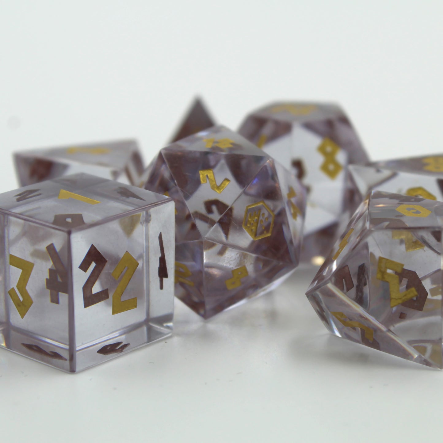 Cubic Zirconia dice set arranged on a white surface and background with the d20 center and the 20 face, which has the Dice Dungeons logo, facing the viewer.