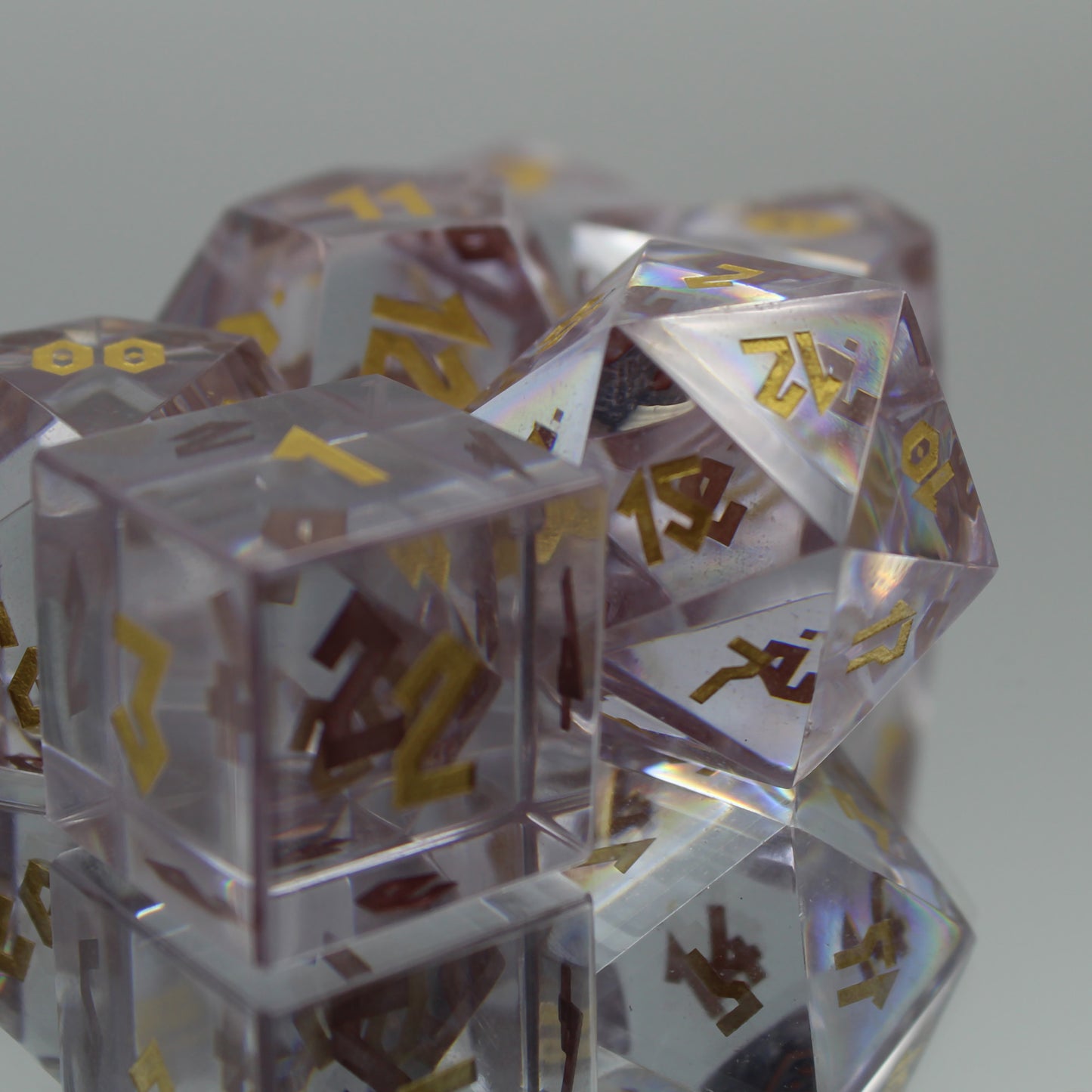 Cubic Zirconia dice set on a reflective surface arranged in a group with the d20 catching the light and in focus with the 12 face toward the viewer.