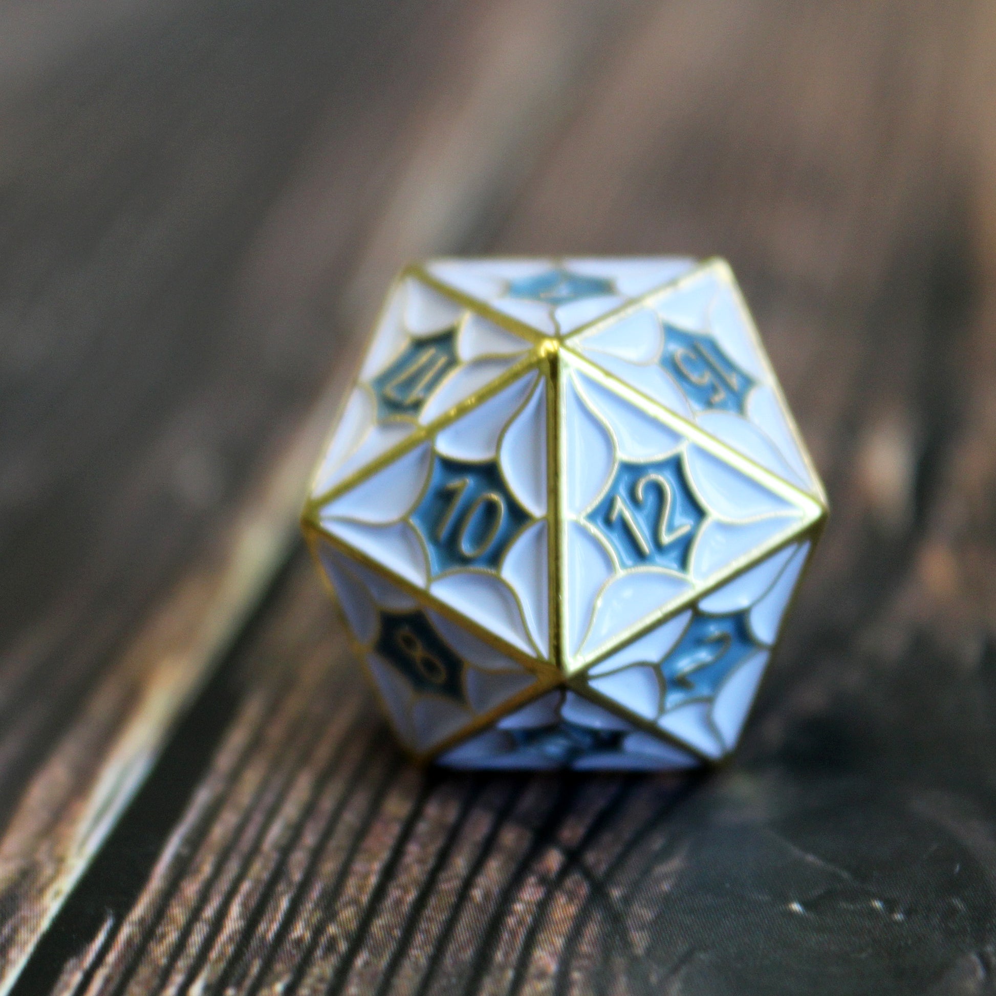 D20 die from the Metal DragonScale White Dice Set on a wooden table, showcasing dragon scale pattern for DnD.