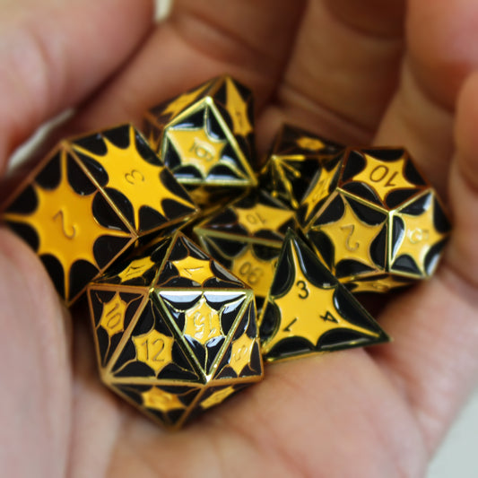 Dragonscale Dice in hand. Gold color metal scales with inset black and yellow enamel. Numbers are gold. 
