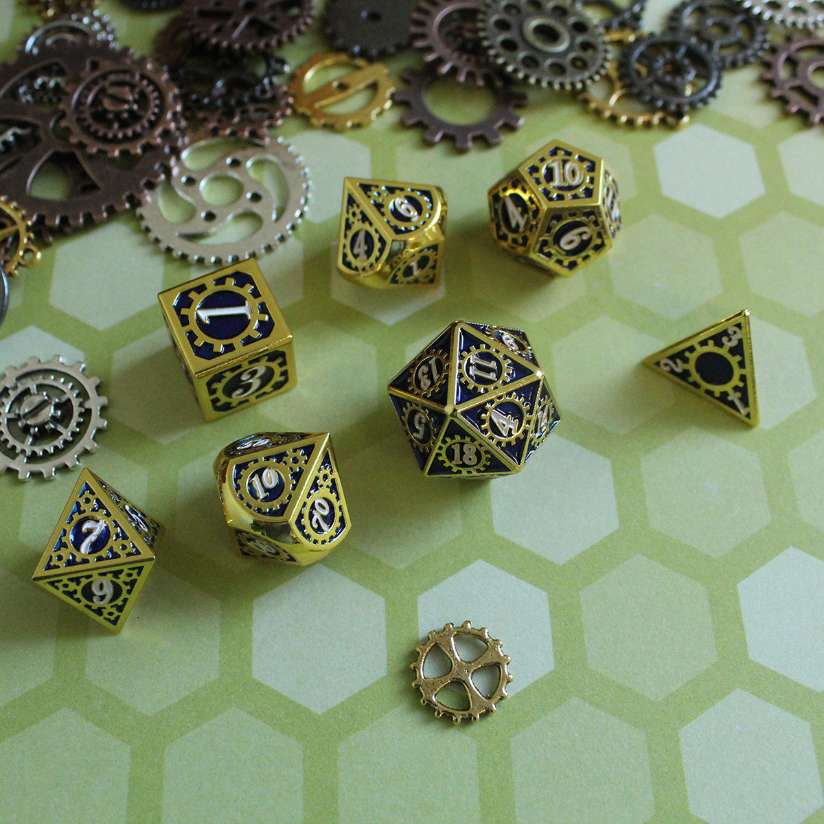 Display shot of the Mechanist blue and gold RPG dice set on a green surface with hexagons and decorative cogs and gears around.