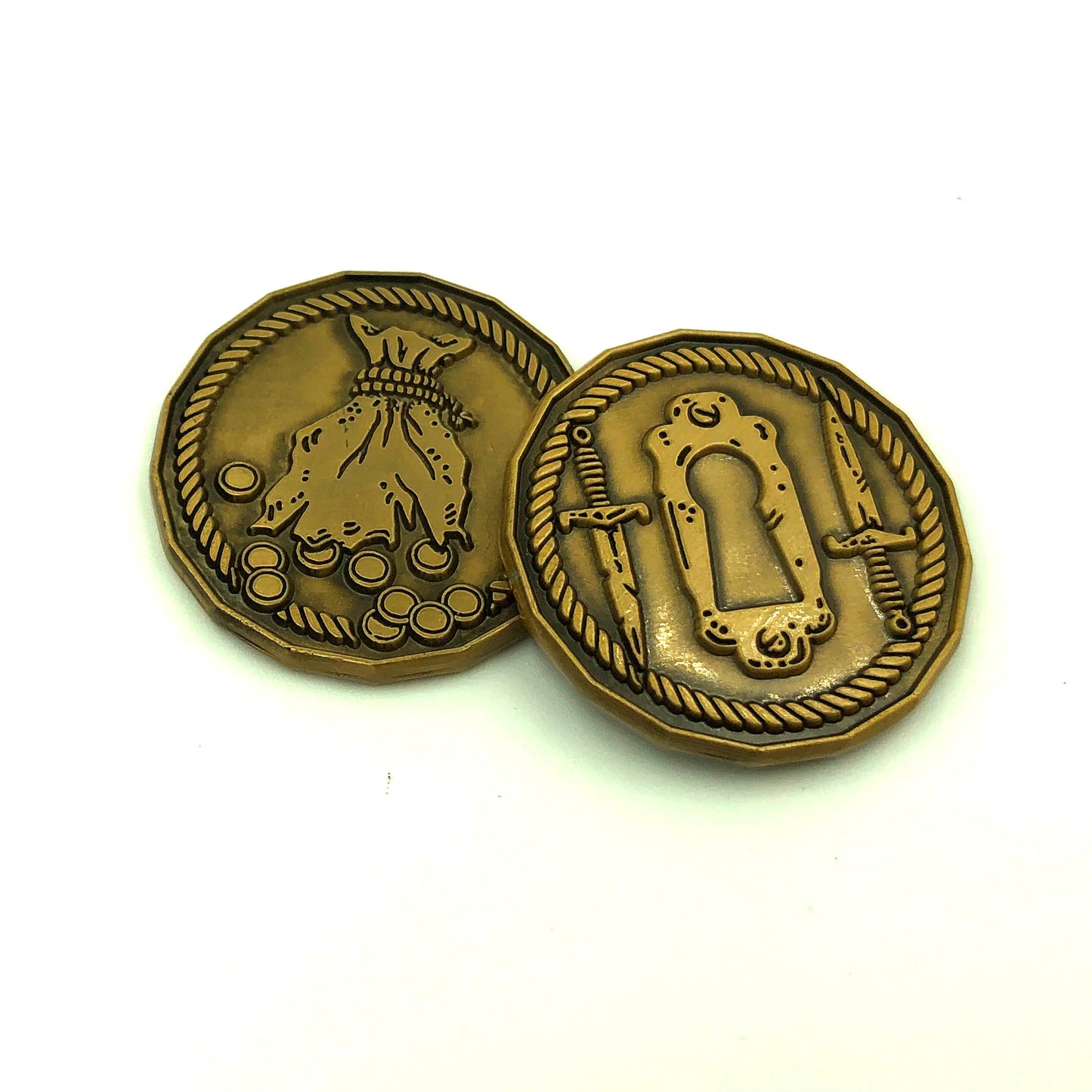 Rogue Character Coin front and back on a white surface featuring a front side with daggers and a keyhole and a back side of a spilled coin pouch. These coins are sized for a 1 inch grid and may be used as miniatures or counters.